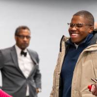 four people standing, two in forefront laugh together